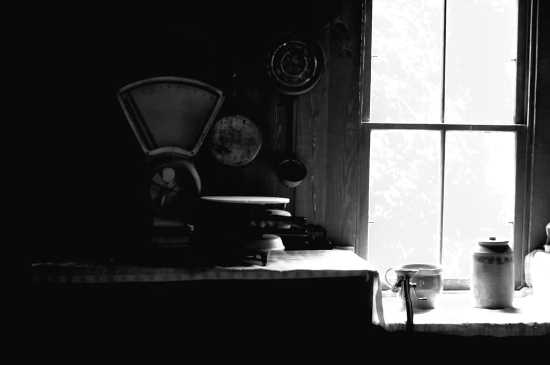 A black and white photo of a chair and a window